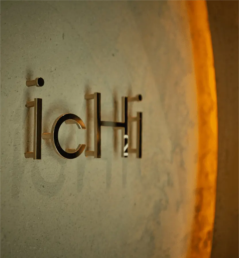 レストラン「ICHI」の壁面に設置された、温かみのある照明に照らされた金属製のロゴサインのクローズアップ